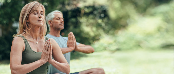 a man and woman meditating outside
